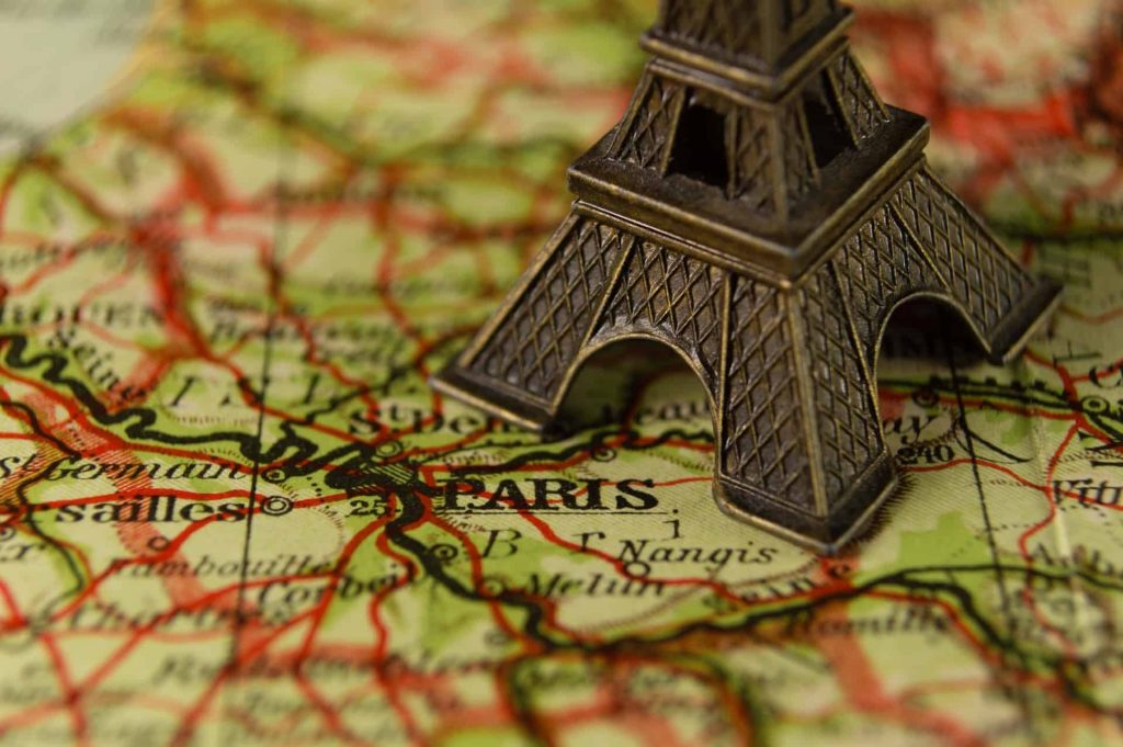 Miniature Eiffel Tower on a map of France just next to Paris