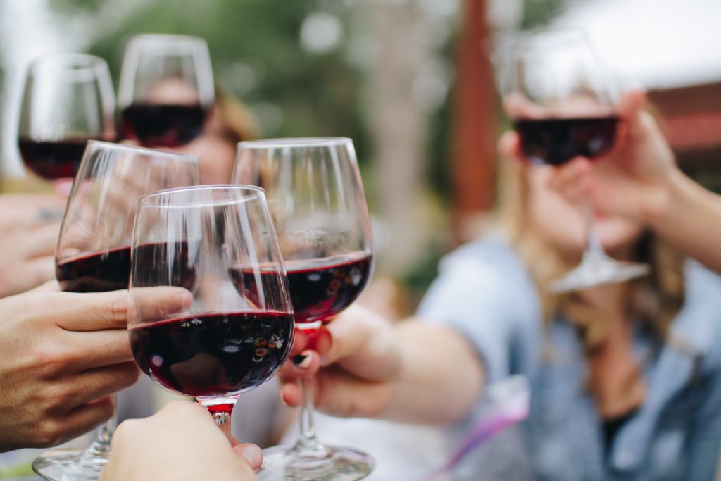A photo of half a dozen French friends clinking glasses of red wine in cheers
