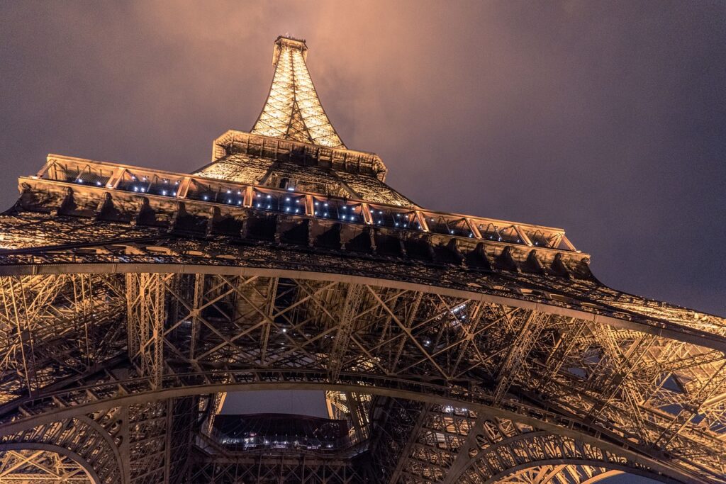A photo looking up the Eiffel Tower at night while it is illuminated.