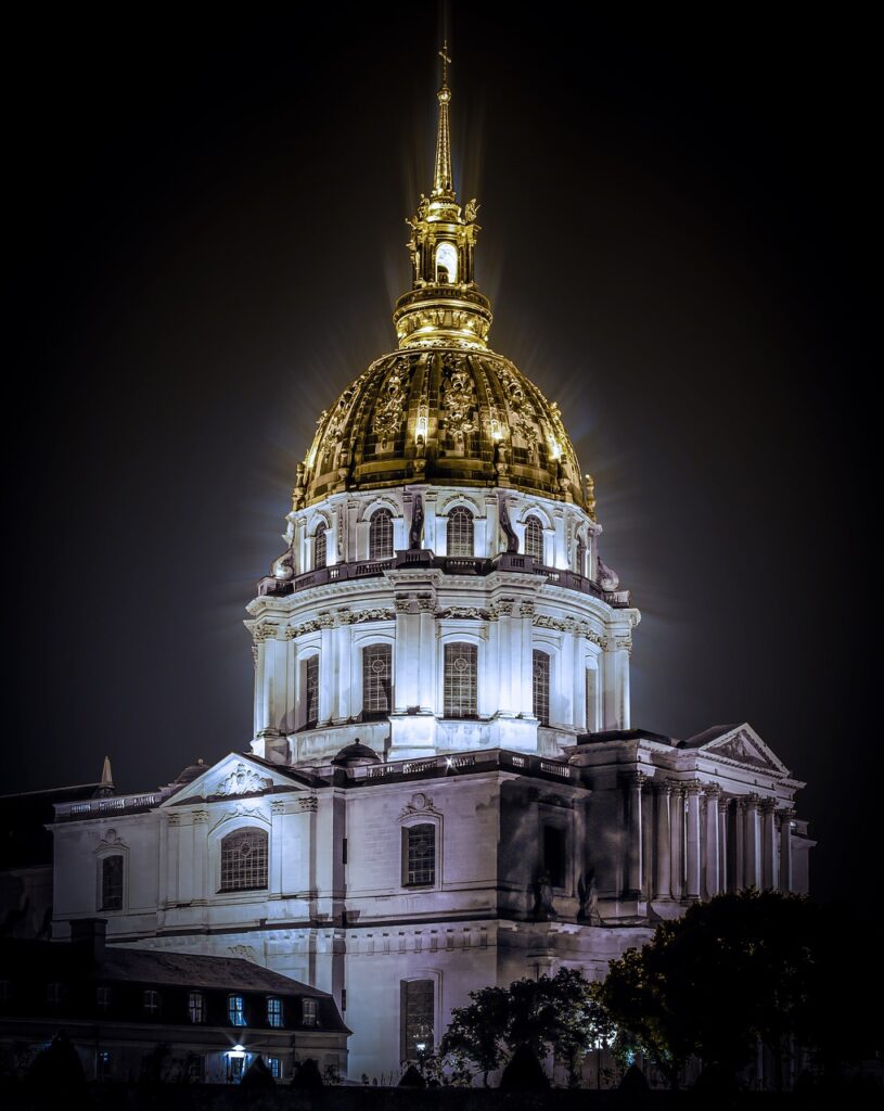 A photo of the gold dome of Invalides illuminated at night.