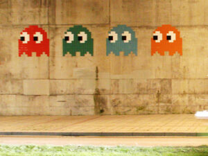 A photo of Space Invader artwork in the shape of four pacmen mounted on a wall.