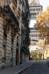 A photo of an empty street in Paris. The Eiffel Tower can be seen behind the building at the end of the road.