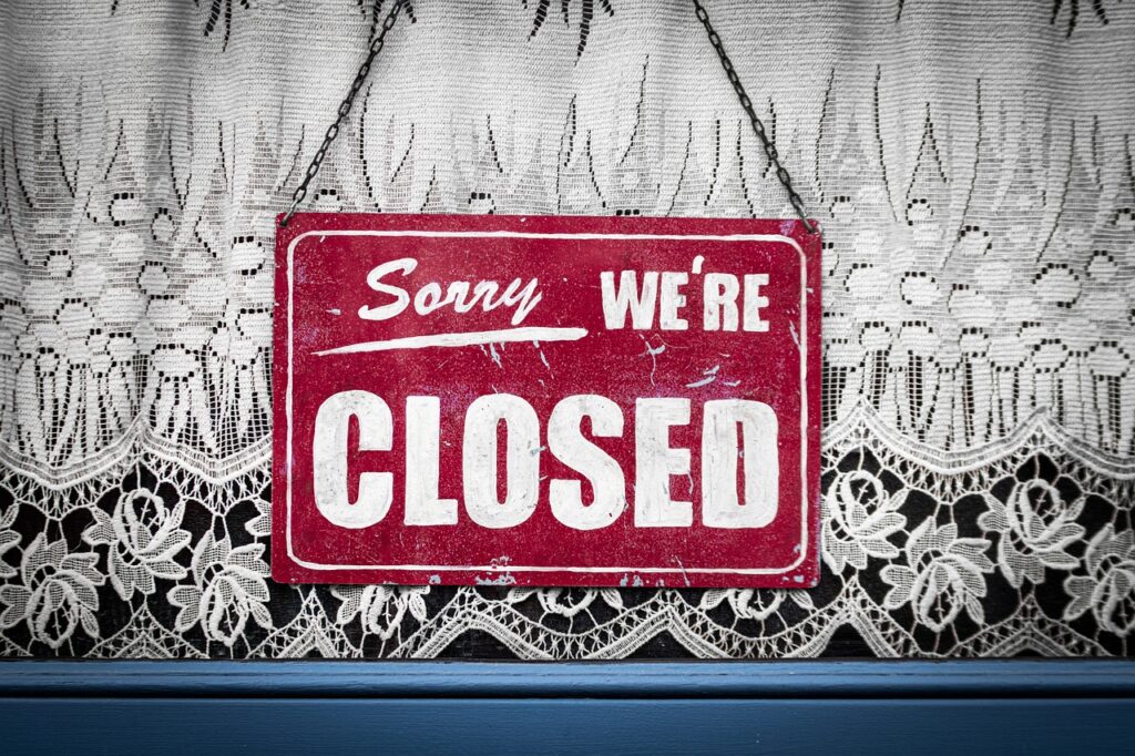 A photo of a red sign that says in white lettering "Sorry We're Closed"
