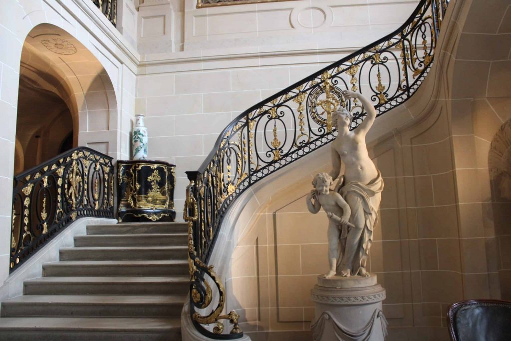 A photo of the grand stairwell of the Musée Nissim de Camondo with a statue of a woman and child at the base.