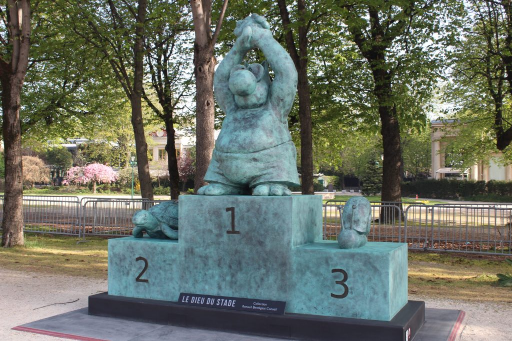 A photo of a bronze sculpture with a cat atop a podium. A turtle is on the second place position and a snail is in third.
