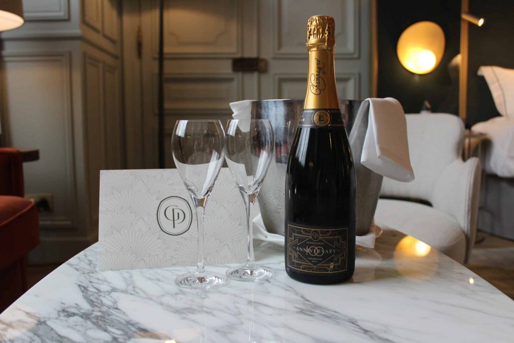 A photo of a champagne bottle, ice bucket, and two champagne glasses on a marble coffee table.