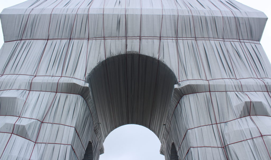A close up photo of the Arc de Triomphe Wrapped, looking up at the Arc from the centre at street level.