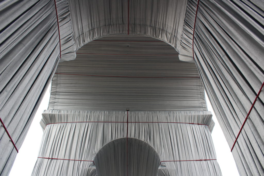 A photo of the underside of the Arc de Triomphe Wrapped. The photo was taken from street level, looking directly up at the underside of the wrapped arc.