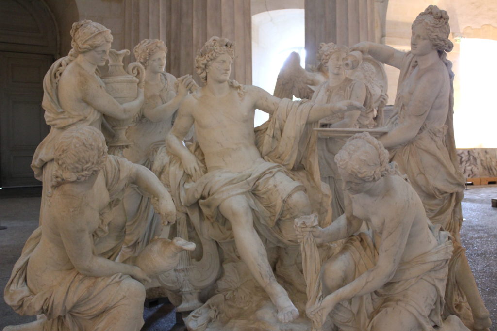 A photo of a scene of statues. A man is reclining in the centre, while several servants surround him, catering to his every whim.