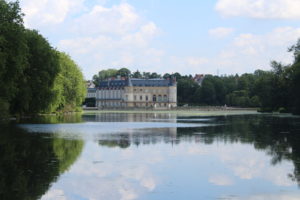 A photo of Château de Rambouillet in the distance. The photo was taken looking across a lake at the chateau.