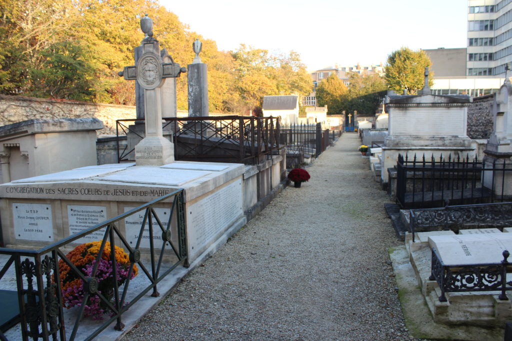 A photo of the interior of the Picpus Cemetery showing an aisle of graves.