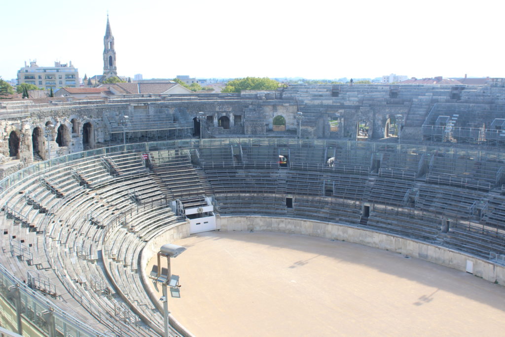 A photo of the interior of the Arena of Nîmes. It is taken from the top of the stands looking down into the pit.