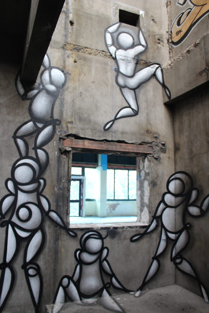 An image of graffiti cartoon people crawling up a wall of an abandoned building.