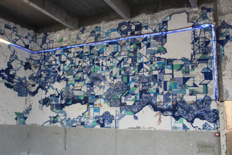 An image of an abstract mural of graffiti art on the wall of an abandoned building as part of L'Essentiel exhibition.