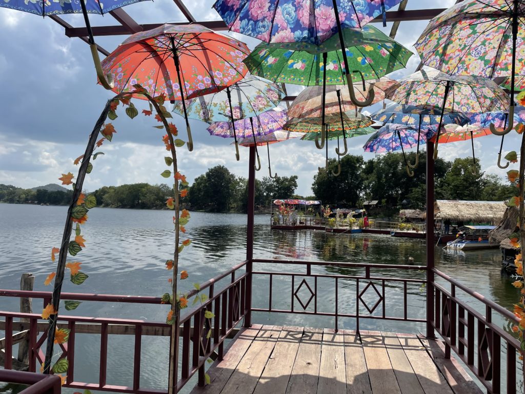 A photo from a travel trip to Cambodia. It shows a dock on a lake with umbrellas forming an arch overhead.