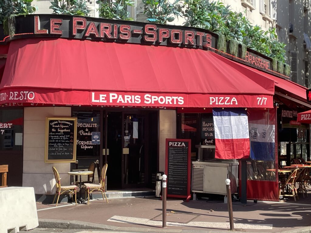 A photo of a restaurant in Paris during the Rugby World Cup. The restaurant is called Le Paris-Sports, and a French flag is hanging out front.