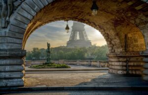 A photo of the Eiffel Tower as seen in the background through an archway over an alleyway.