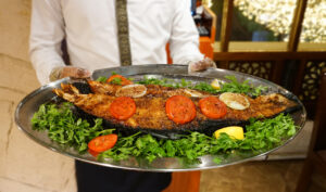 A close up photo of a plate of food. It is a full fish with lots of garnishes.